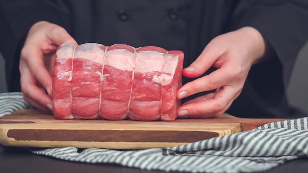 Schritt für Schritt. Roher Schweinebraten ohne Knochen auf Holzschneidebrett mit Gewürzen.