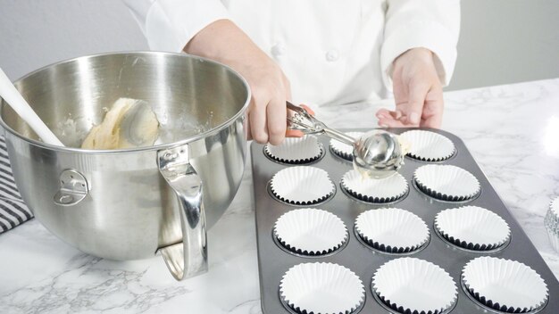 Schritt für Schritt. Schaufeln Sie den Teig mit einem Teiglöffel in eine Cupcake-Form, die mit Cupcake-Förmchen ausgelegt ist.