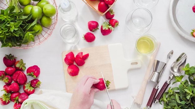 Schritt für Schritt. Schneiden von Früchten für Erdbeer-Mojito aus frischen Bio-Erdbeeren.