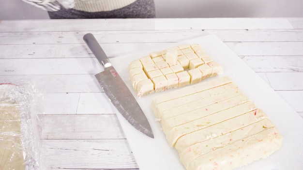 Schritt für Schritt. Schneiden von hausgemachtem Candy Cane Fudge auf einem weißen Schneidebrett.