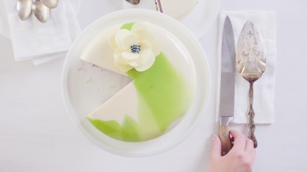 Schritt für Schritt. Schneiden von Mousse-Kuchen mit Spiegelglasur auf dem Tisch.