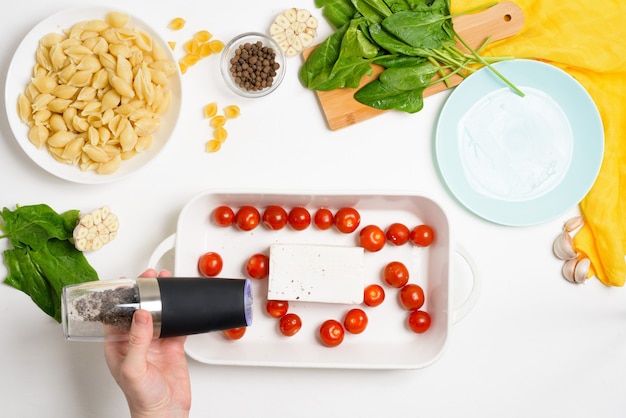 Schritt-für-Schritt-Zubereitung und Zutaten für ofengebackenen Feta-Käse mit Tomaten und Nudeln, Pfeffer-Knoblauch-Draufsicht, Trendrezept.