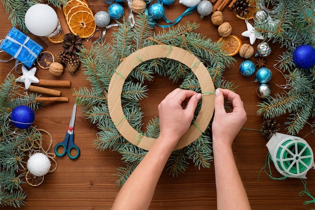 Schrittweise Anleitung zur Herstellung eines Weihnachtsbaumkranzes zu Hause aus Fichtenzweigen, Orangen und Weihnachtskugeln