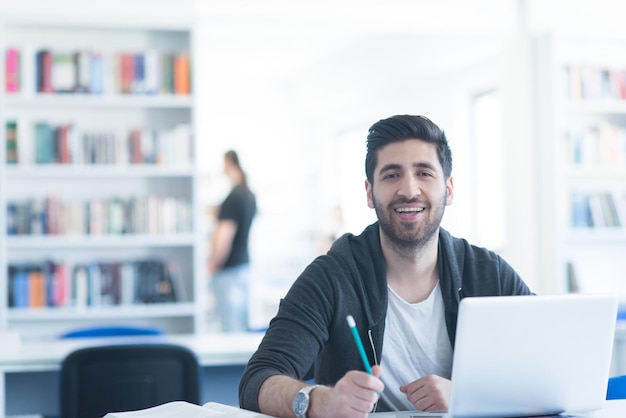 Schüler bereiten sich auf eine Prüfung vor und lernen Lektionen in der Schulbibliothek, recherchieren auf einem Laptop und surfen im Internet