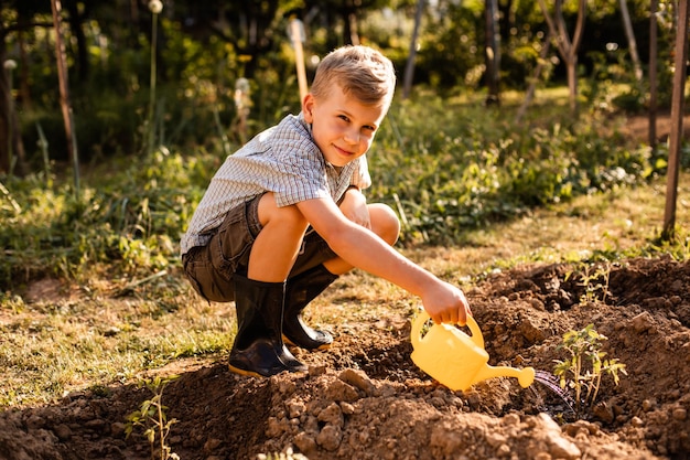 Schüler Bewässerung Tomatenpflanzen im Garten