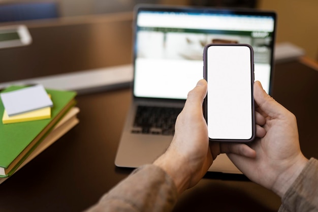 Foto schüler, der ein mobiltelefon mit einem leeren bildschirm hält online-lernen, das sich auf die prüfung vorbereitet mockup