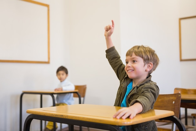 Schüler, der seine Hand an seinem Schreibtisch anhebt