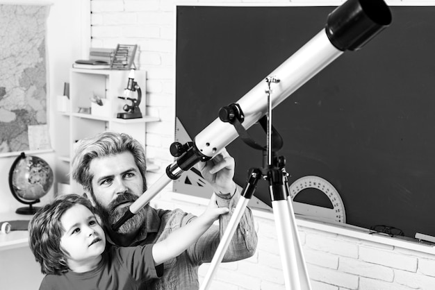 Schüler, der Sterne mit einem Lehrer-Astronomie-Teleskop beobachtet, glückliches, süßes, fleißiges Kind sitzt an einem...