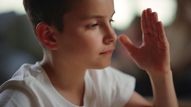 Schüler, der während des Fernunterrichts die Hand hebt Ernster Junge mit Online-Unterricht