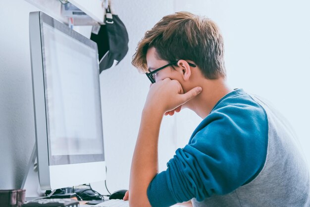 Foto schüler, der zu hause einen computer benutzt, um hausaufgaben zu machen, teenager, der online-homeschooling-konzept studiert