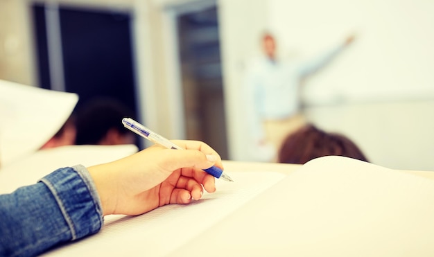 Schüler, die beim Vortrag mit der Hand auf ein Notizbuch schreiben