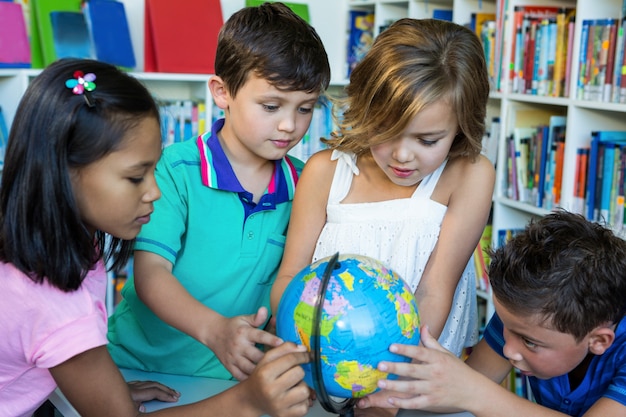 Schüler, die Globus in der Schulbibliothek betrachten