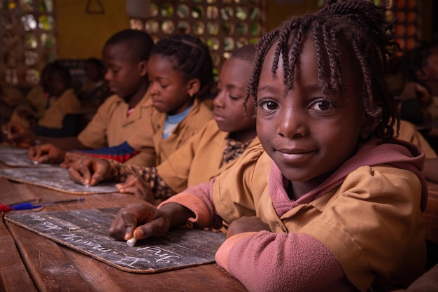 Schüler einer Schule in Afrika nehmen den Unterricht und schreiben mit Kreide Notizen auf eine Tafel Kinder in einer Schule in Afrika