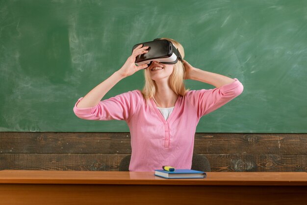 Schüler lesen mit VR-Brille auf einer Tafel. Schulmädchen mit Virtual-Reality-Headset. Ausbildung am Gymnasium mit zukunftsweisender Bildungstechnologie.