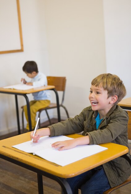 Schüler schreiben im Editor an seinem Schreibtisch lächelnd