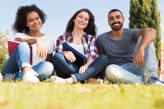 Schüler sitzen auf dem Rasen des Schulcampus