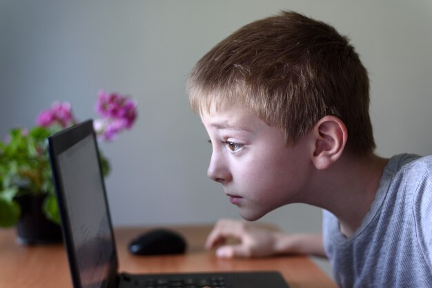 Schüler sitzt seine Nase in einem Laptop begraben. Internet und Vorschulkind