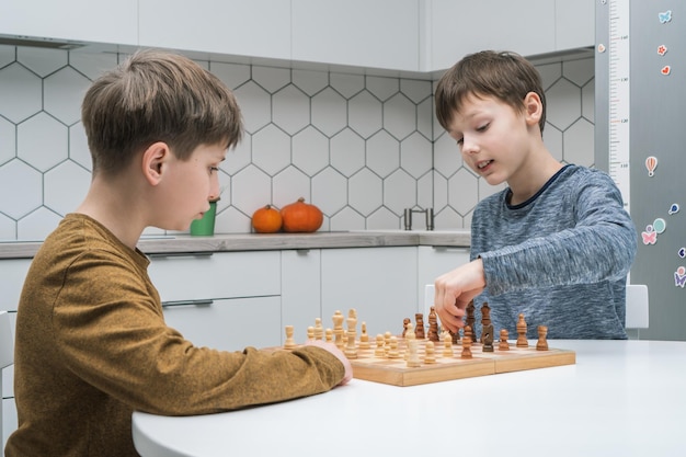 Schüler spielen Schach auf Küchentisch Seitenansicht Schachbrett mit schwarzen und weißen Figuren Spielstrategie-Taktiken