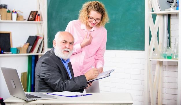 Schüler verwirrt durch einige Informationen Schüler fragt Lehrer nach Aufgabe Lösen von mathematischen Aufgaben Schulbildungskonzept Hausaufgaben überprüfen Erzieher und Schüler betrachten Buch Erklären eines schwierigen Themas