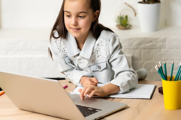 Schülerin kleine Schulmädchen Hausaufgaben auf Laptop-Computer silbernem Hintergrund