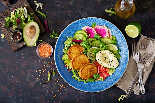 Schüssel-Abendessentabelle des strengen Vegetariers Buddha. Gesundes Essen. Gesunde vegane Lunch Bowl. Krapfen mit Linsen und Radieschen, Avocadosalat. Flach liegen. Ansicht von oben