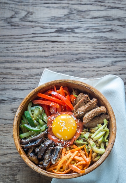 Foto schüssel bibimbap auf dem holztisch