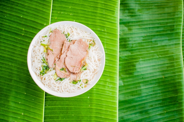 Schüssel der traditionellen vietnamesischen Rindfleischsuppe Pho Bo auf Bananenblatthintergrund.