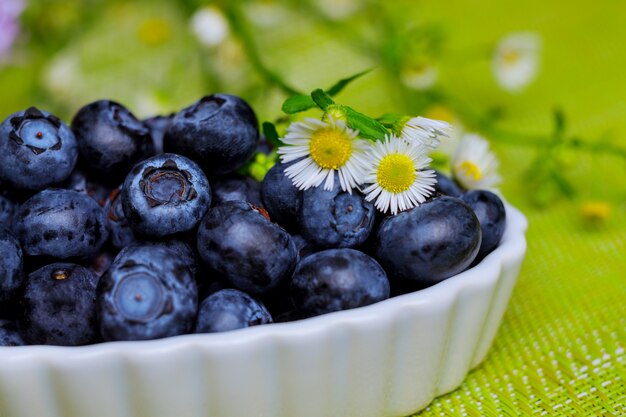 Schüssel frische Blaubeeren auf grünem Tisch.