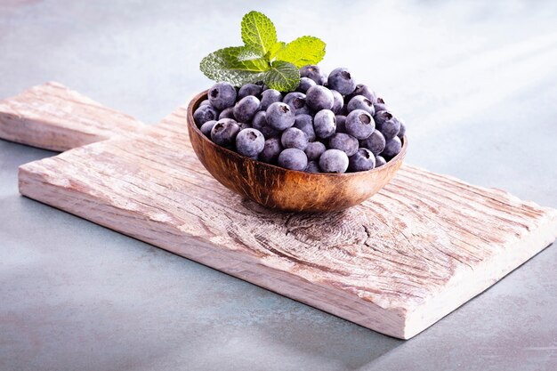 Schüssel frische Blaubeeren auf rustikalem Holzbrett