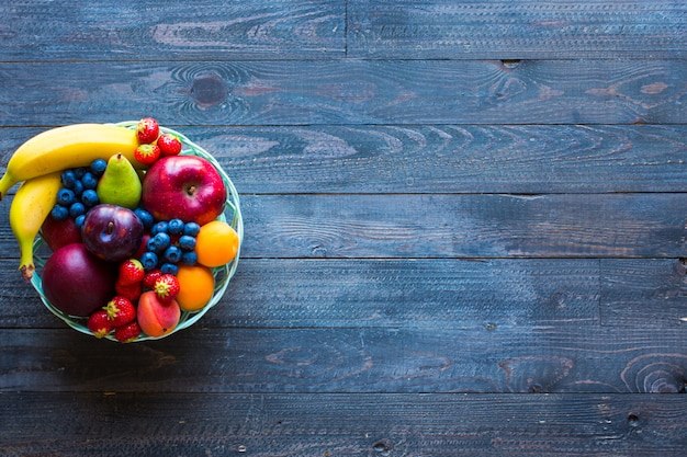 Schüssel frische Frucht mit Banane, Apfel, Erdbeeren, Aprikosen, Blaubeeren, Pflaumen, ganzen Körnern, Gabeln, Draufsicht