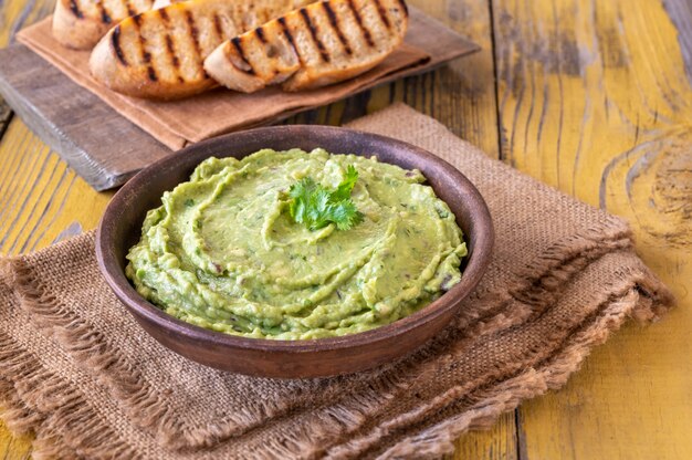 Schüssel frische Guacamole auf rustikalem Hintergrund