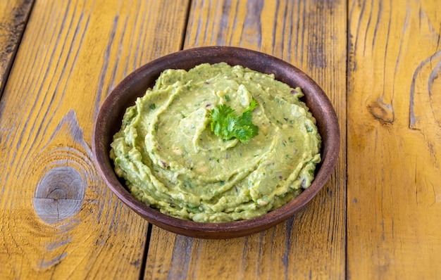 Schüssel frische Guacamole auf rustikalem Hintergrund