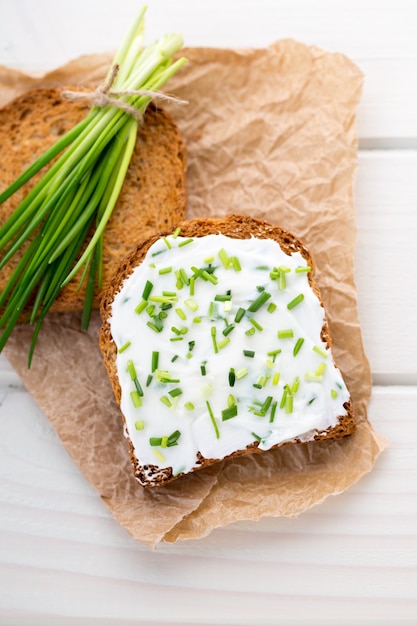 Schüssel Frischkäse mit Frühlingszwiebeln, Dip-Sauce auf Holztisch.