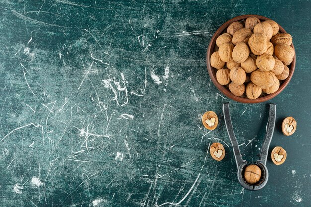 Schüssel geschälte Walnüsse mit Nussknackwerkzeug auf Marmortisch.