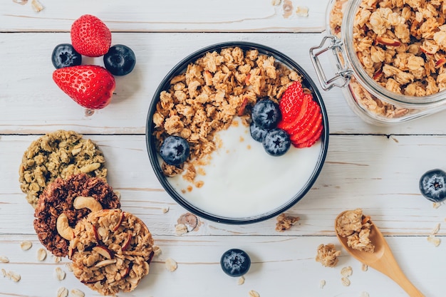 Schüssel Granola mit Joghurt, frische Beeren, Erdbeere auf Holztisch.