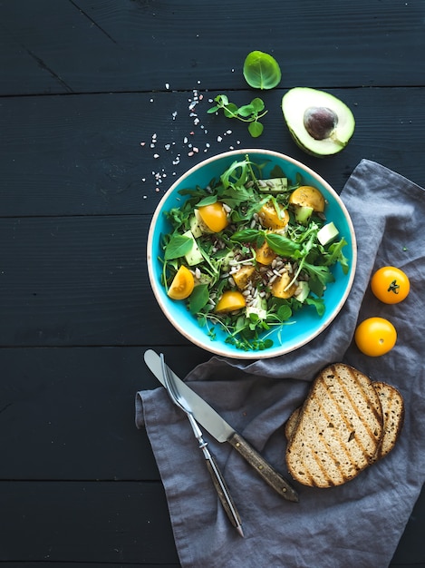 Schüssel grüner Salat mit Avocado, Rucola, Kirschtomaten und Sonnenblumensamen, gegrillten gezüchteten Scheiben und frischen Kräutern