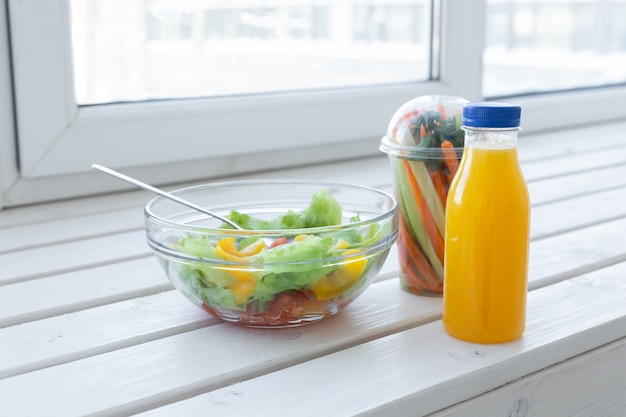 Schüssel grüner Salat, rohes Gemüse und Flasche Orangensaft. Gewichtsverlust, Ernährung und richtig