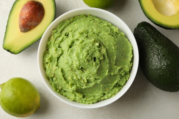 Schüssel Guacamole, Avocado und Limette auf weißem strukturiertem Hintergrund, Draufsicht