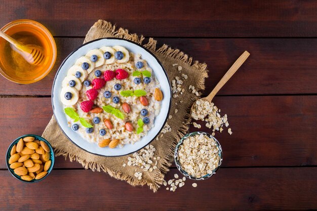 Schüssel Haferbrei mit Beeren, Honig und Früchten auf Burlap, schmackhafte Haferfleisch mit Himbeeren