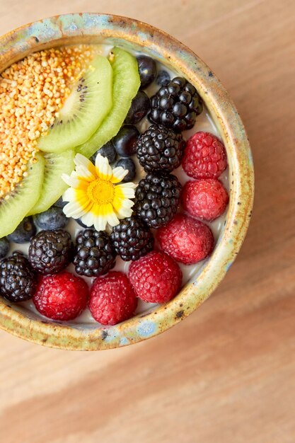 Schüssel Haferflocken mit Brombeer-Himbeer-Amaranth und Kiwis auf einem Holztisch