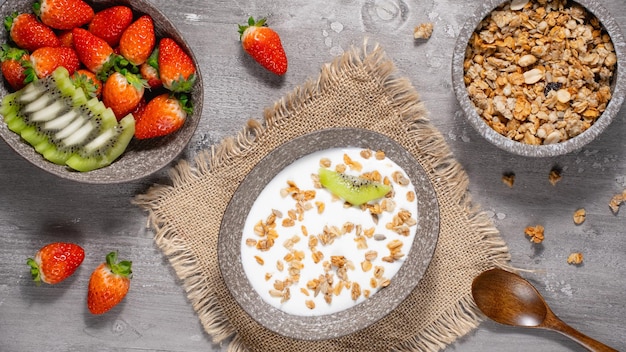 Schüssel hausgemachtes Müsli mit Joghurt und frischen Beeren auf Holzhintergrund von oben