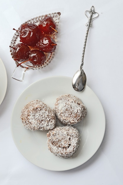 Schüssel mit Apfelmarmelade, Dessert, einer Tasse mit einem Getränk auf einer Untertasse und einem silbernen Löffel auf einem weißen Hintergrund.