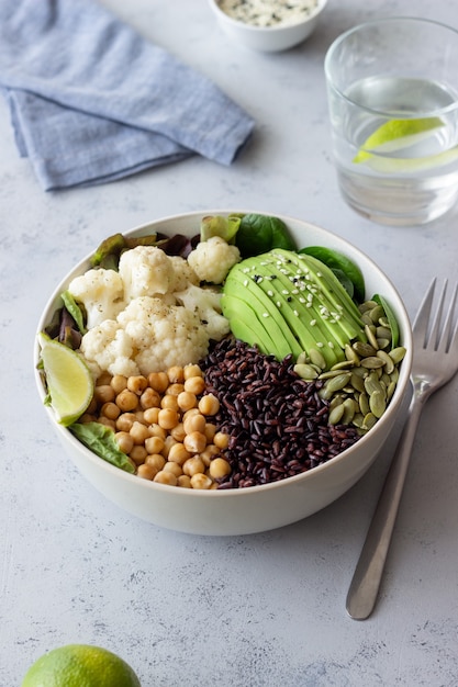 Schüssel mit Avocado, schwarzem Reis, Kichererbsen, Kohl, Spinat und Salat. Gesundes Essen. Vegetarisches Essen.