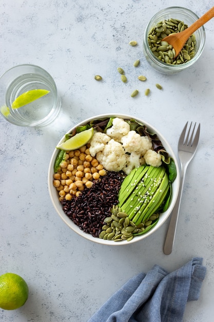 Schüssel mit Avocado, schwarzem Reis, Kichererbsen, Kohl, Spinat und Salat. Gesundes Essen. Vegetarisches Essen.