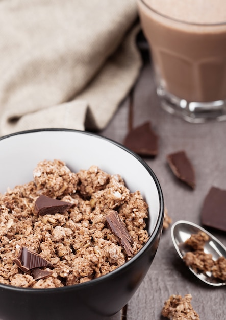 Schüssel mit Bio-Schokoladen-Müsli-Frühstücksflocken auf Holz mit Schokoriegel auf Holz