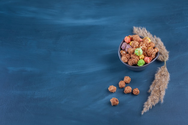 Schüssel mit bunten Müslikugeln auf einem Blau platziert.