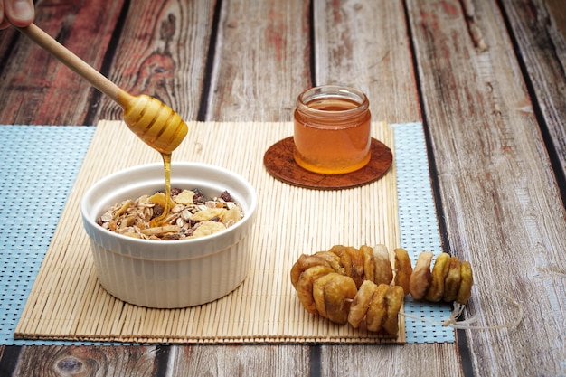 Schüssel mit einer flachen Hafermahlzeit mit frischem Honig und einer Frucht auf dem Holztischhintergrund.