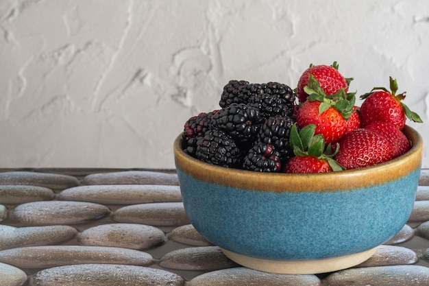 Foto schüssel mit erdbeeren und brötchen auf einem steintisch saisonfrüchte