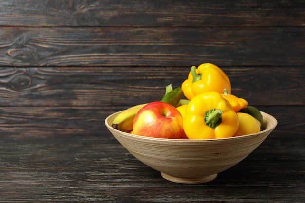 Schüssel mit Gemüse und Obst auf Holzuntergrund