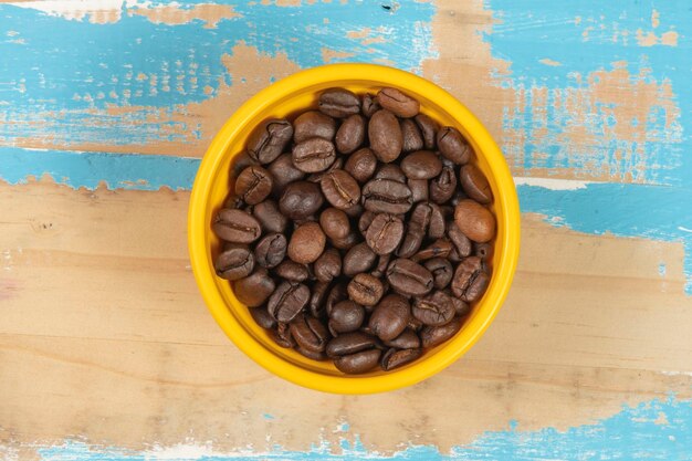 Schüssel mit gerösteten Kaffeebohnen auf blauem rustikalem Holztisch